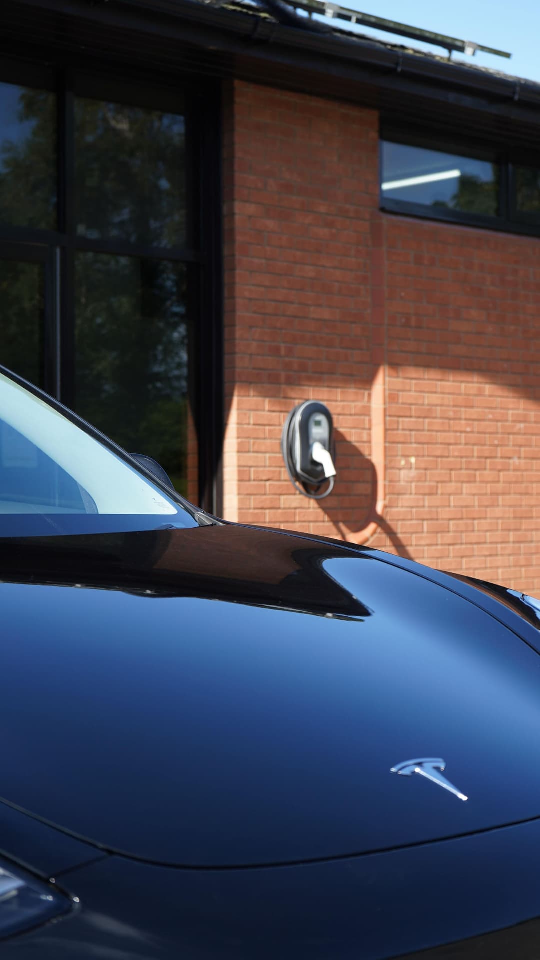 Blue Tesla with EV home charger in the background