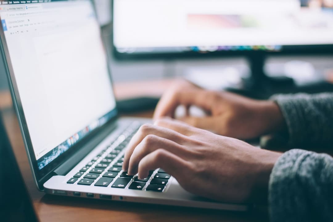 Hands typing on an Apple Macbook laptop 